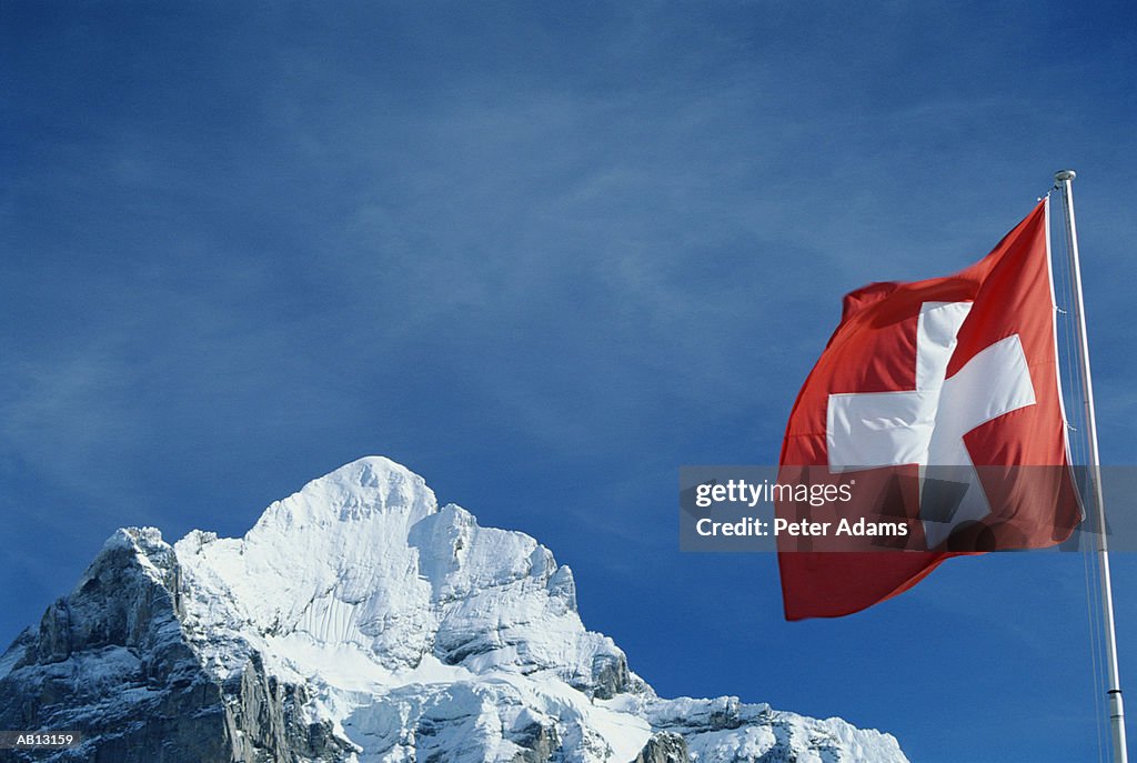 Switzerland, Wetterham, Swiss flag on snow-covered mountain peak