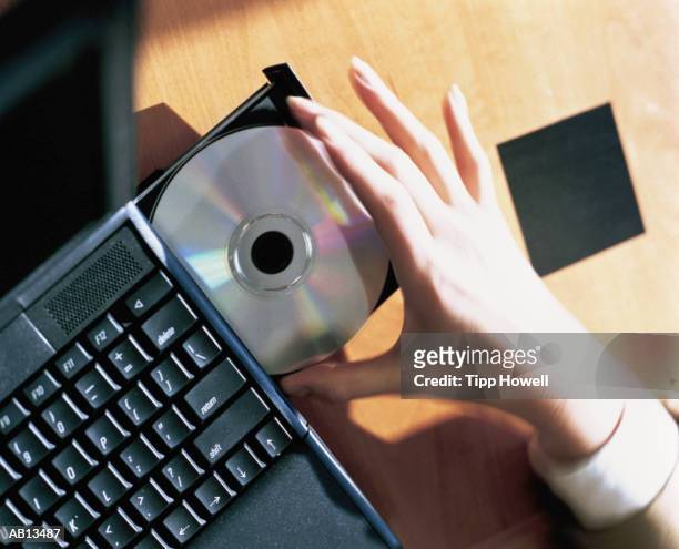 woman removing compact disc from laptop, close-up, elevated view - rom stock pictures, royalty-free photos & images