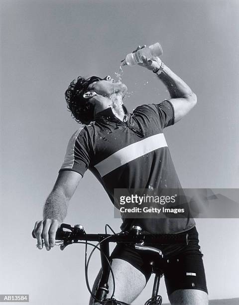 male mountain biker pouring water into mouth from water bottle, (b&w) - cycling vest stock pictures, royalty-free photos & images