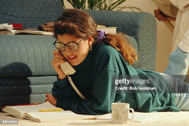 teenage girl (16-18) talking on phone, looking at homework on floor - landline phone imagens e fotografias de stock