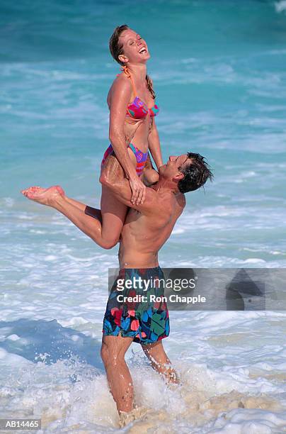 man lifting woman up on beach, guana cay, bahamas - ilhas ábaco imagens e fotografias de stock