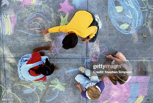 four children (7-10) drawing with chalk on pavement, overhead view - krijt kunstnijverheiduitrusting stockfoto's en -beelden