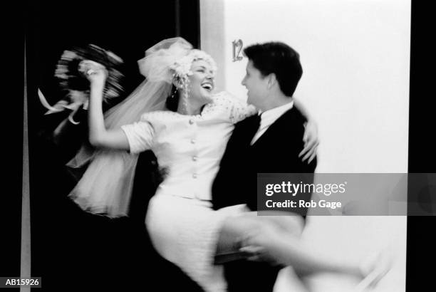 groom carrying bride over threshold (b&w) - sposa foto e immagini stock