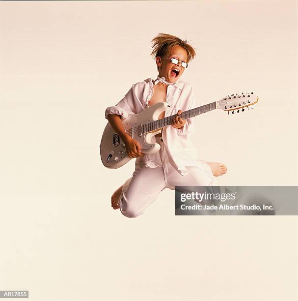 boy (8-10) jumping in mid-air, playing guitar - air guitar stockfoto's en -beelden