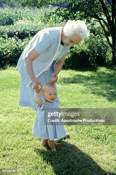 grandmother walking baby girl (9-12 months) in garden - apostrophe stock pictures, royalty-free photos & images
