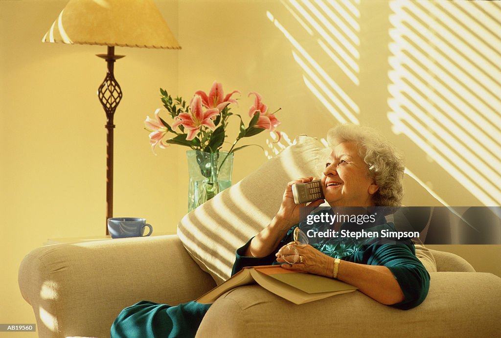 Mature woman in arm chair using telephone