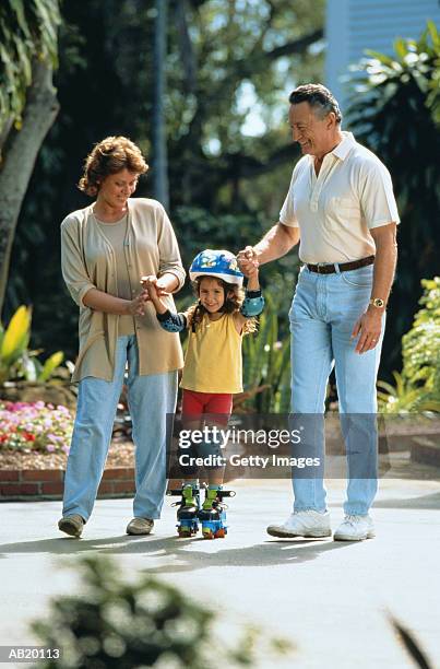 grandparents helping granddaughter (4-6) to rollerskate - coudière photos et images de collection