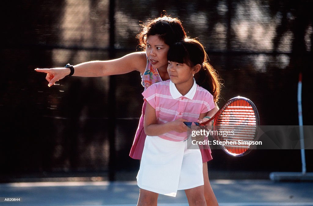 Woman teaching girl (11-13) to play tennis