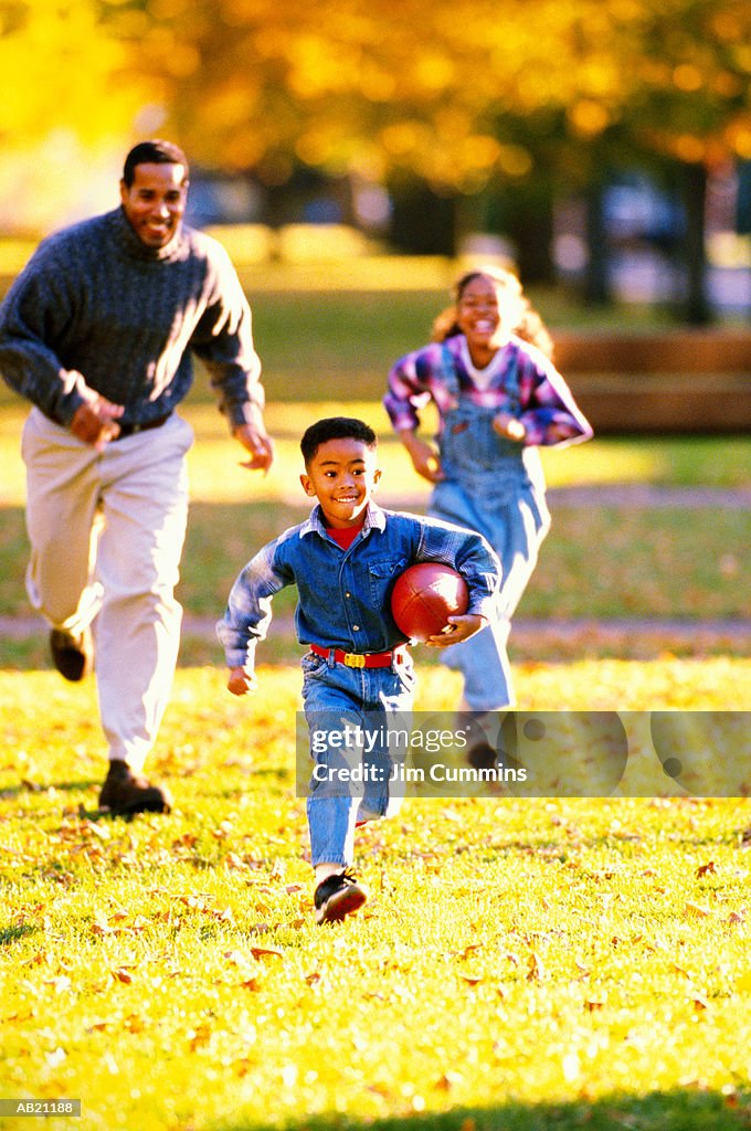 Man playing American football with son (4-6) and daughter (8-10)