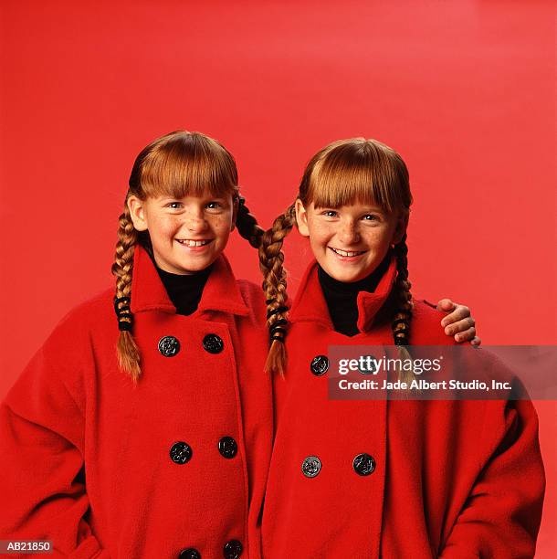 twin girls (8-10) wearing matching coats and pigtails - gémellité photos et images de collection