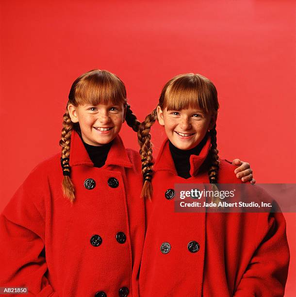 twin girls (8-10) wearing matching coats and pigtails - twin stock pictures, royalty-free photos & images
