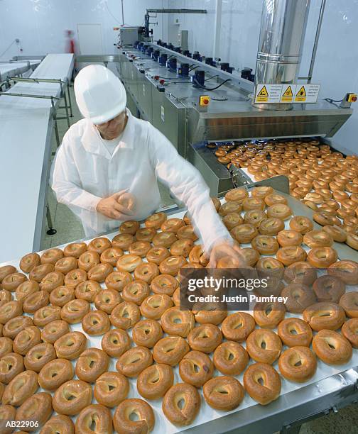 male worker in protective clothing at bagel factory, elevated view - bread packet stock pictures, royalty-free photos & images