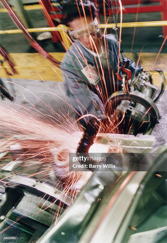 Production line worker spot welding car panels, elevated view
