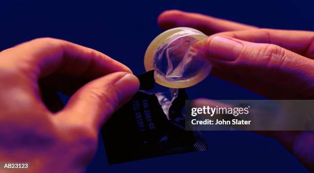 person removing condom from packet, close-up - condoms stock pictures, royalty-free photos & images