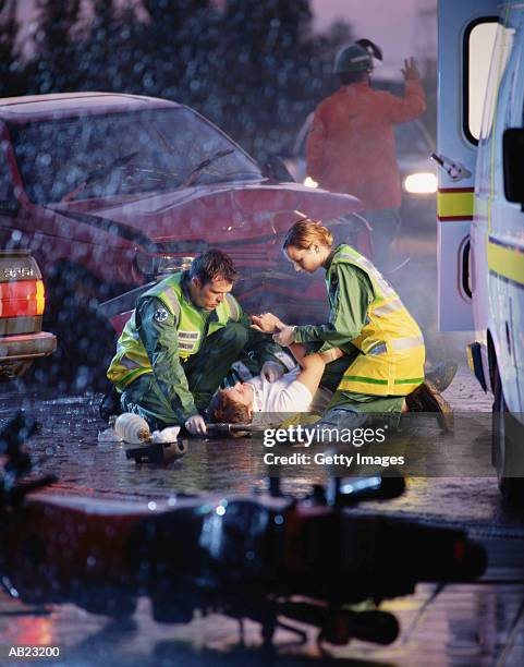 paramedics attending to victim at scene of car crash - victim foto e immagini stock