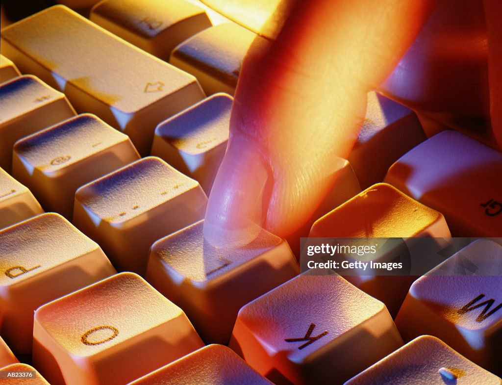 Finger hitting letter on computer keyboards, blurred motion, close-up