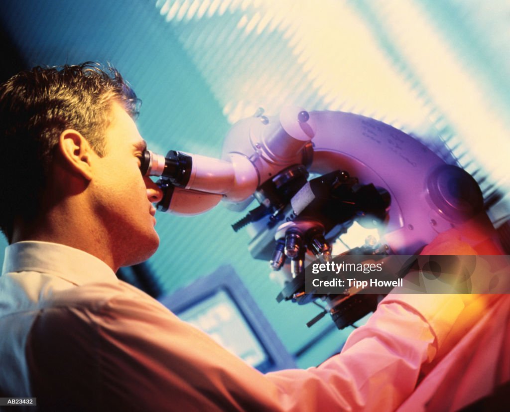 Researcher looking through microscope, close up