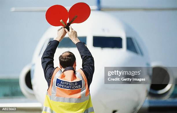 airfield operator signaling to airplane - air traffic control stock-fotos und bilder