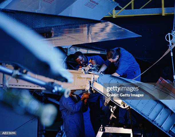 flight engineers working on wing flap of airplane - flugzeugteil stock-fotos und bilder