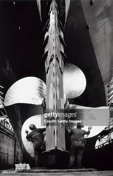men working on propeller of ship in dry dock at ship yard, (b&w) - ship propeller stock pictures, royalty-free photos & images