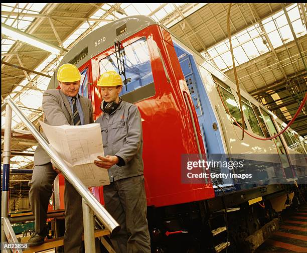 two engineers looking over plans in train manufacturing plant - derby derbyshire photos et images de collection