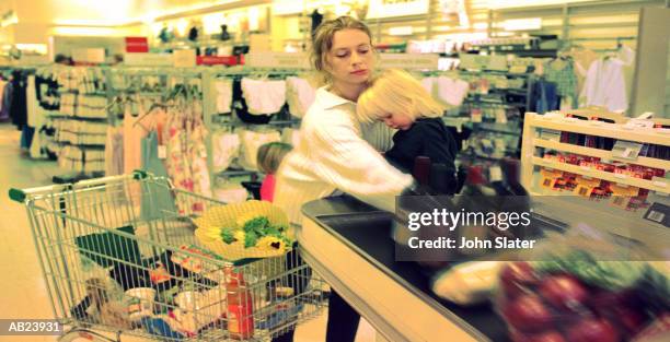 mother and daughter (21-24 months) at checkout in supermarket - checkout conveyor belt stock pictures, royalty-free photos & images