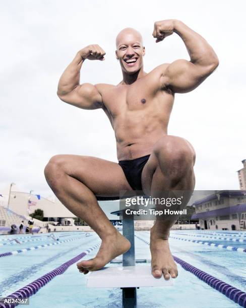 man sitting on diving platform, flexing muscles, portrait - slip de bain de compétition photos et images de collection