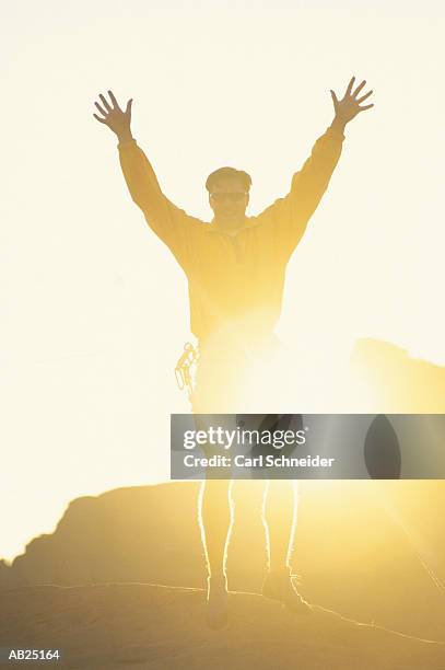 male rock climber on hill with arms stretched out, silhouette - rock hill stock pictures, royalty-free photos & images