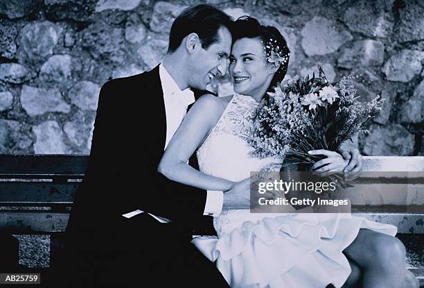 wedding couple with bouquet of flowers on bench outdoors - two toned dress stockfoto's en -beelden