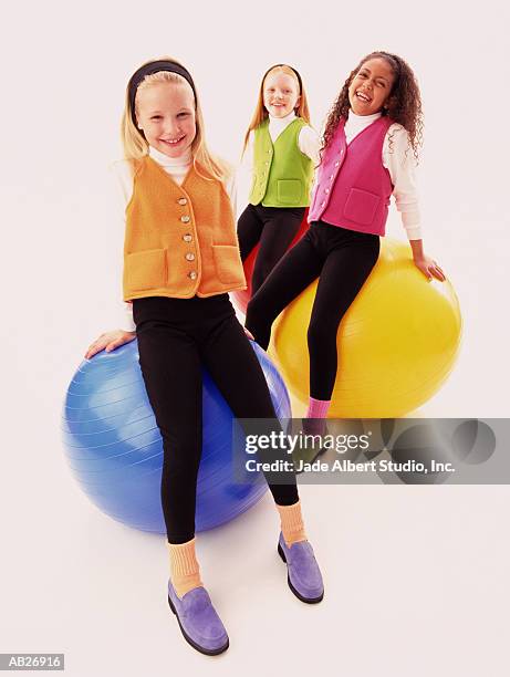 three girls (8-10) sitting on colored beach balls - albert foto e immagini stock