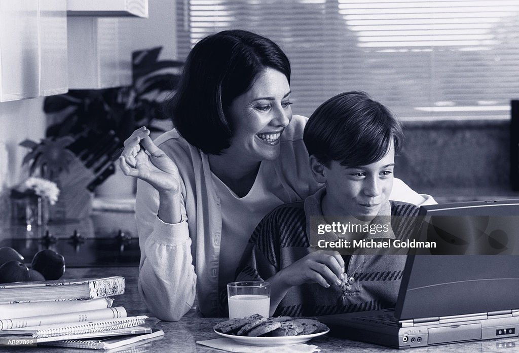 Mother and son (10-12) looking at laptop computer together (B&W)