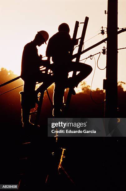 utility linemen repairing cables, silhouette, low angle, dusk - garcia stock-fotos und bilder