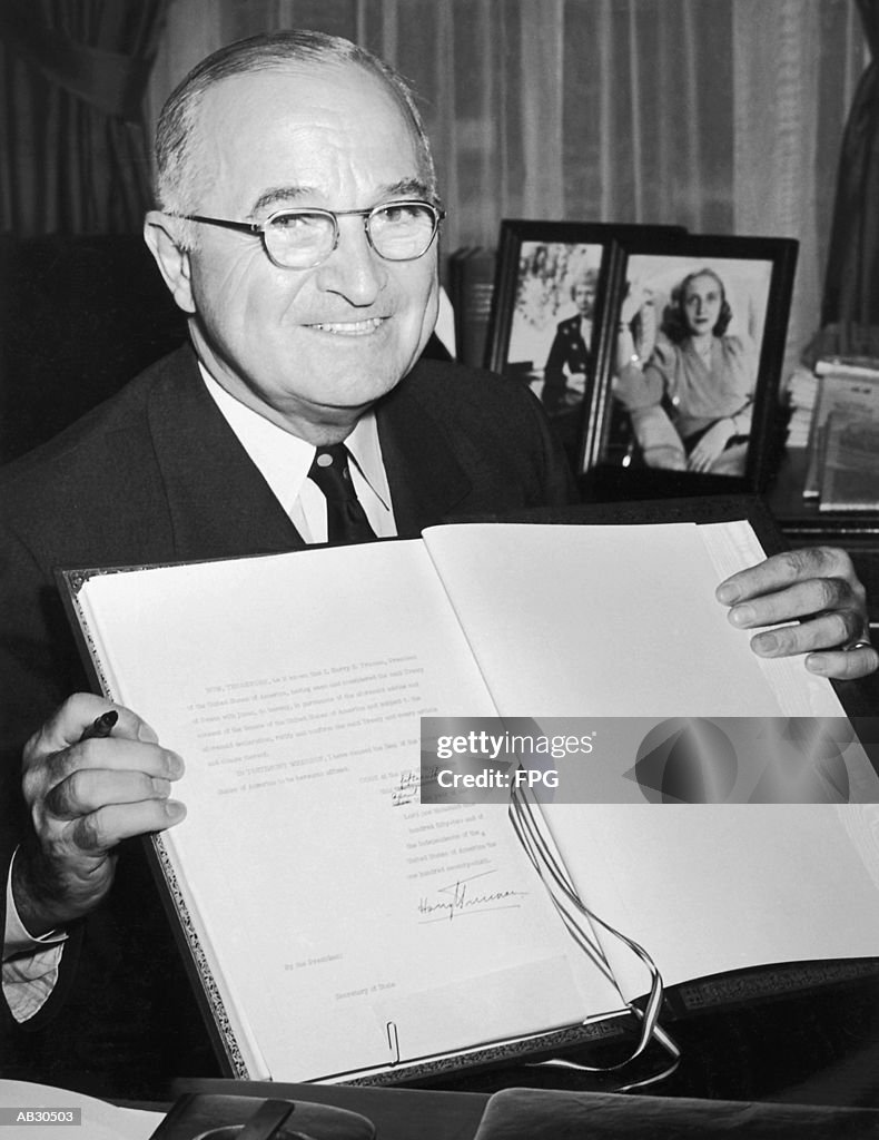 Harry S. Truman holding the NATO Agreement, portrait (B&W)
