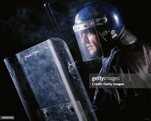 riot police officer with helmet, shield and baton - police in riot gear stock-fotos und bilder