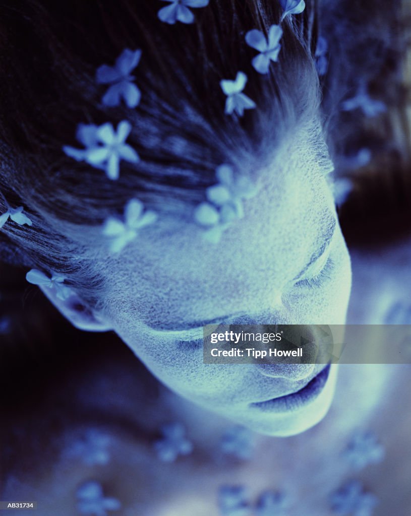 Woman with flowers in hair, close up (blue tone)