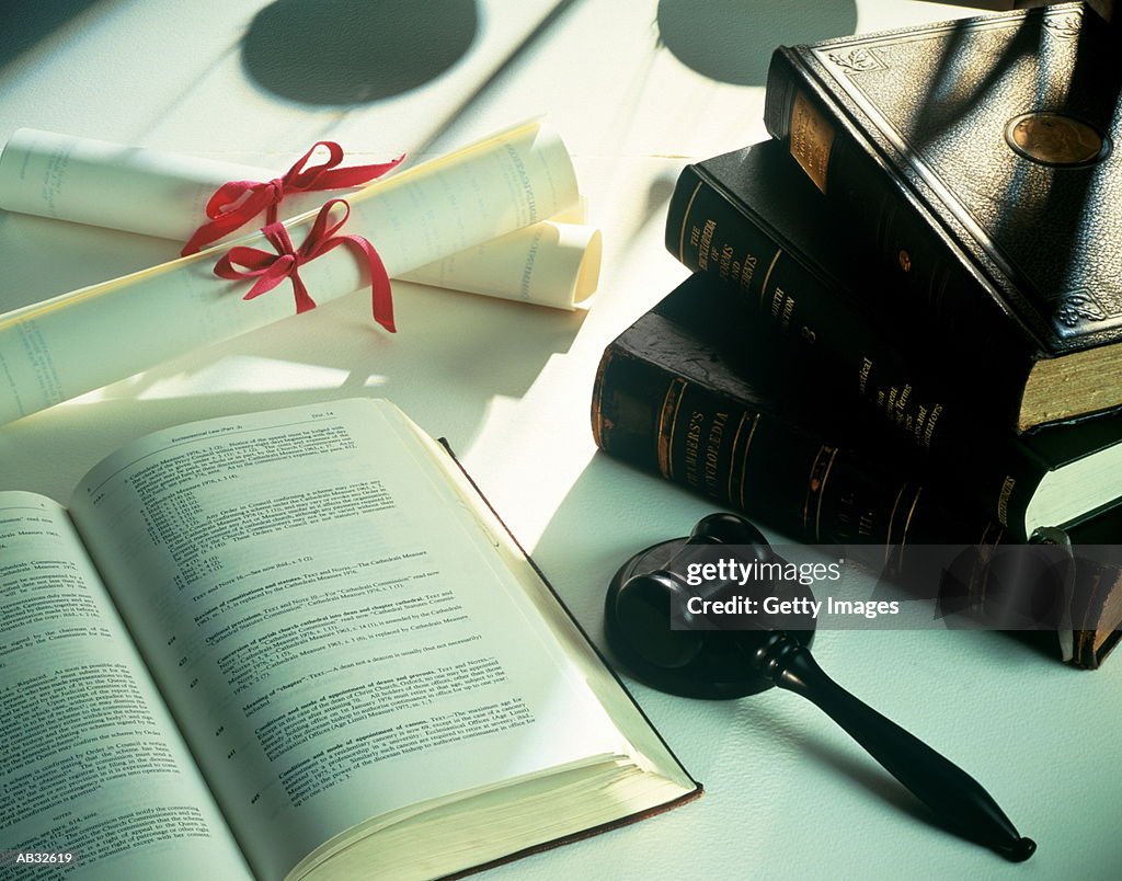 Law books, gavel and scrolls on table, close-up