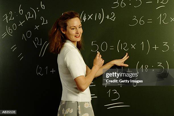 teacher working out math problems on chalkboard - mathematics imagens e fotografias de stock