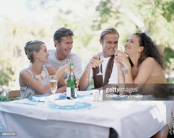 two couples having wine at outdoor table - double date stock pictures, royalty-free photos & images