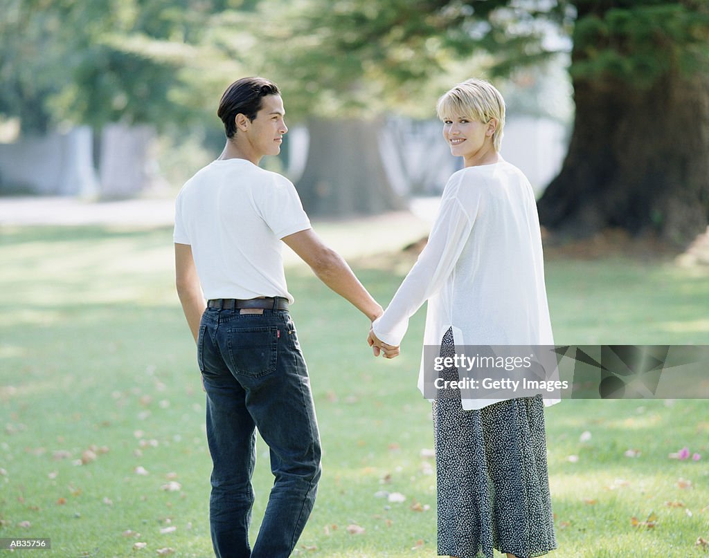 Couple walking through park holding hands