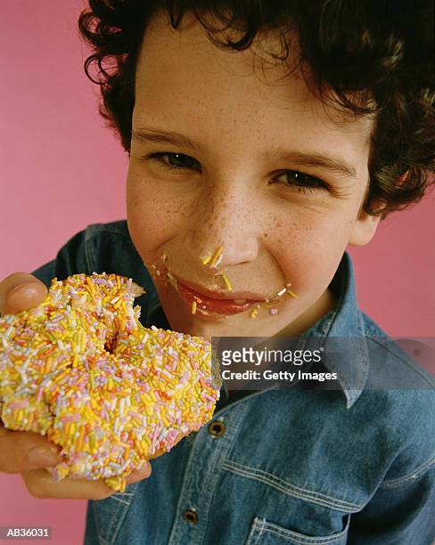 boy (4-6) eating donut with sprinkles, close-up - supersensorial fotografías e imágenes de stock