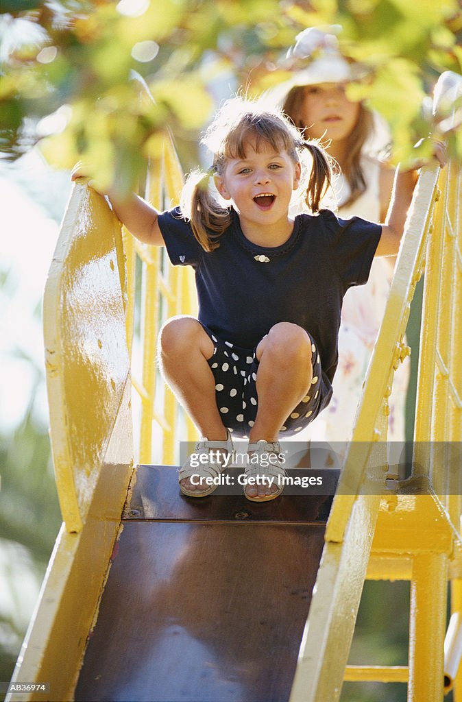 Two girls (4-8) on slide in park