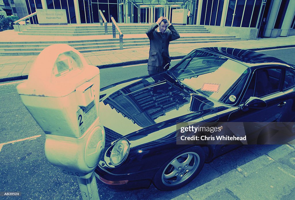 Man looking at parking ticket on car (wide angle lens, blue tone)