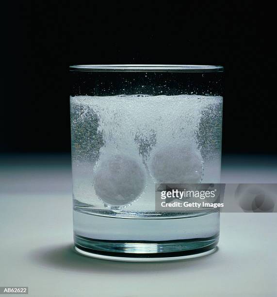 two soluble tablets in glass dissolving in water - dissolving stockfoto's en -beelden