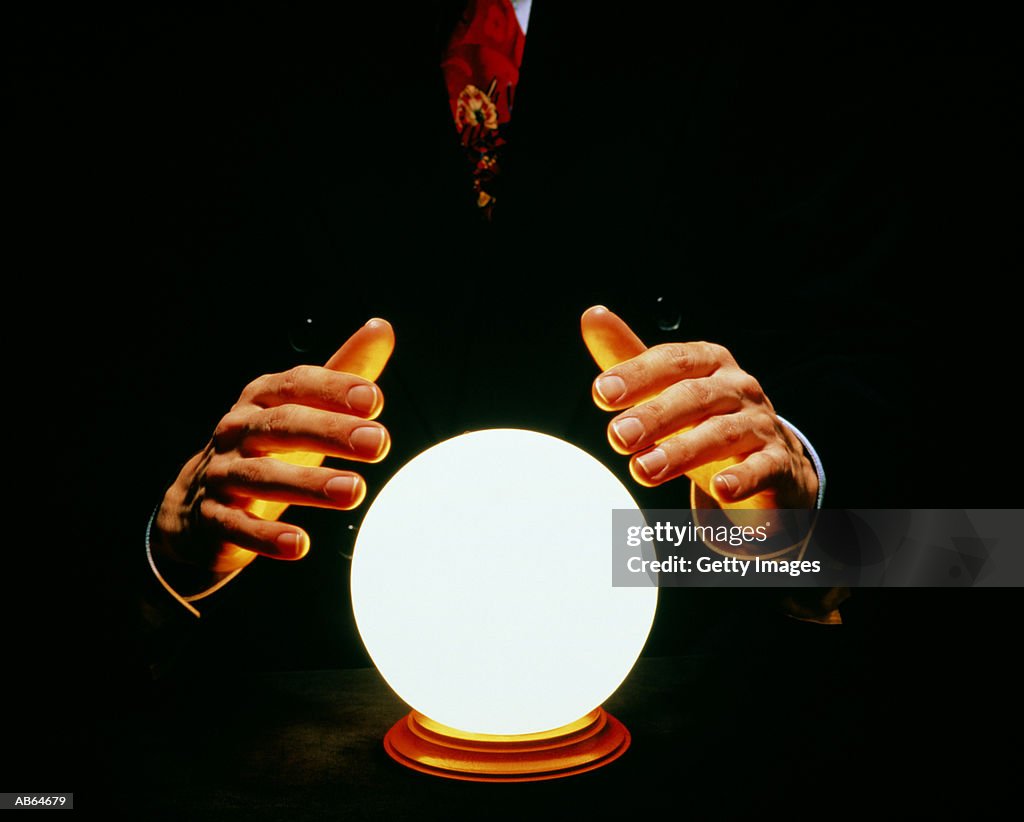 Man in suit with hands around glowing crystal ball