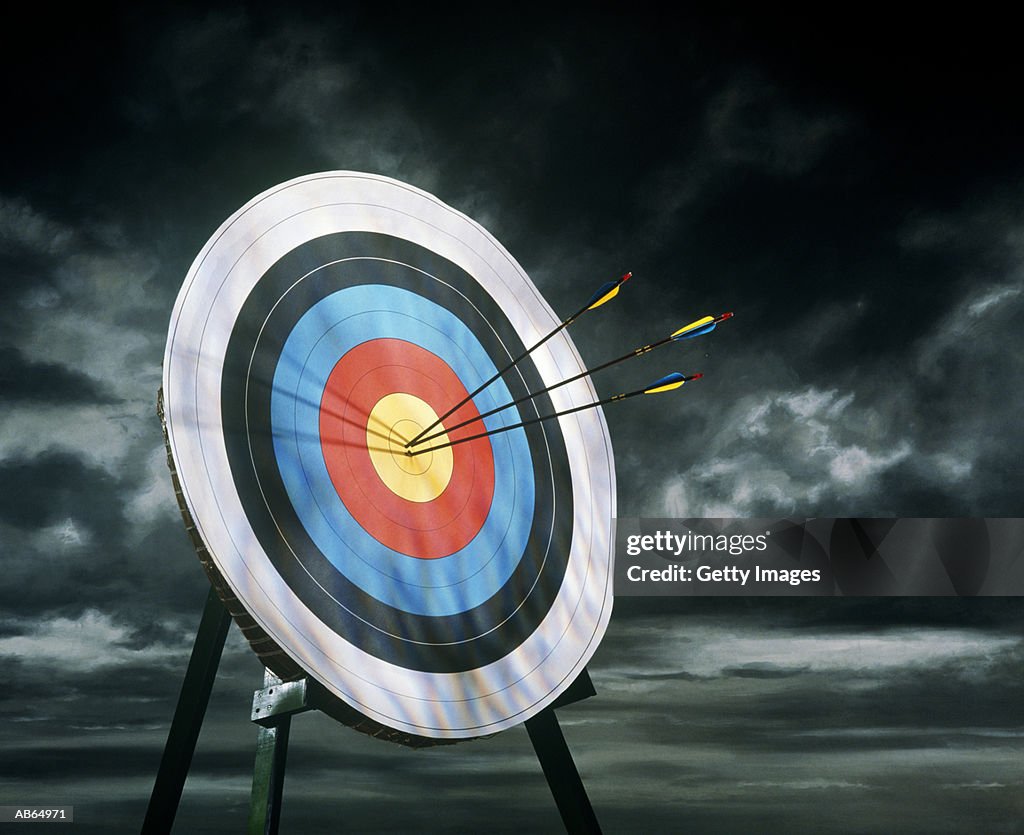 Archery target with arrows, dark clouds in background