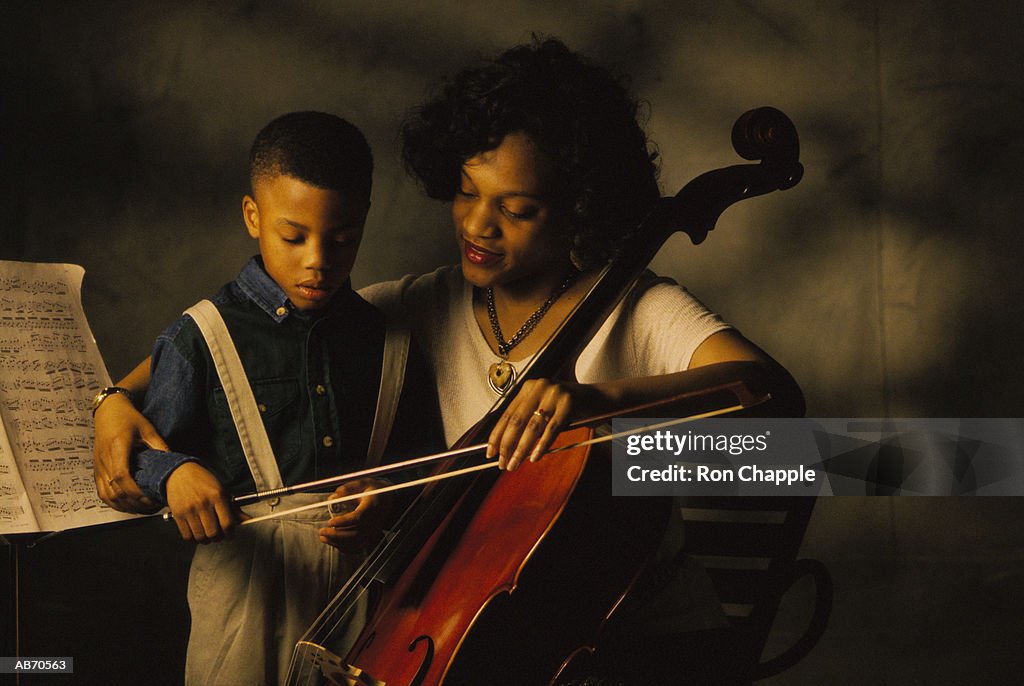 Woman teaching boy (4-6) how to play chello