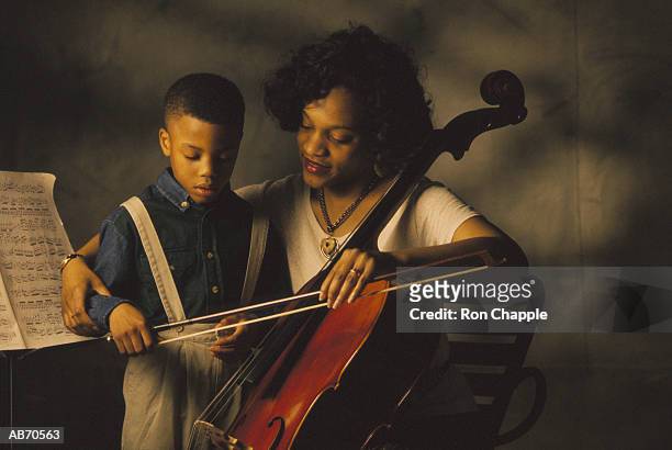 woman teaching boy (4-6) how to play chello - chello stock pictures, royalty-free photos & images