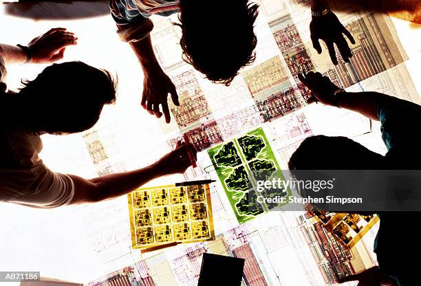 three engineers viewing technical drawings on lightbox, overhead view - lightbox stock pictures, royalty-free photos & images