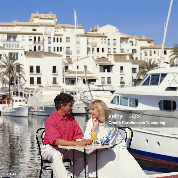 mature couple at table in harbour - a von photos et images de collection