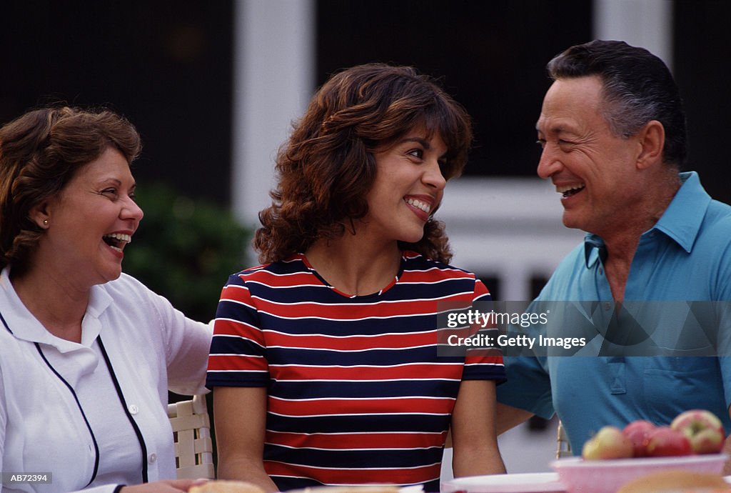 Mature couple and adult daughter outdoors, smiling